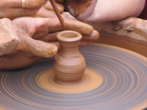 Close-up of hands skillfully crafting pottery with clay on a spinning wheel in a cozy workshop
