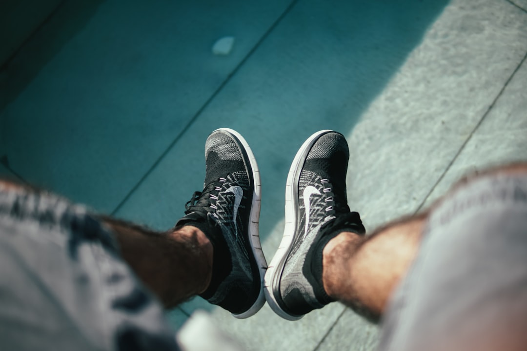 person showing pair of grey-and-white Nike shoes