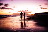couple holding hands while walking on shore