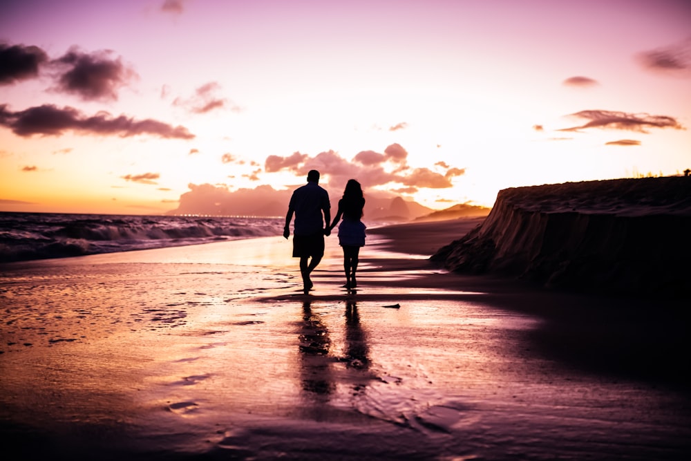 couple se tenant la main en marchant sur le rivage