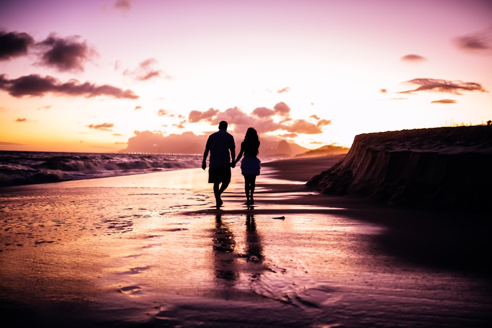 casal de mãos dadas enquanto caminha na praia