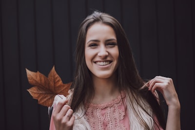 woman holding brown leaf smiling teams background