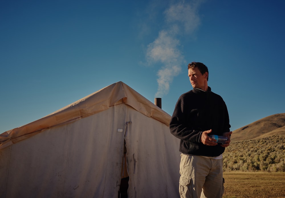 man standing outside white tent