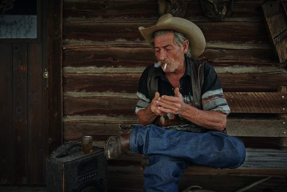 man sitting on brown wooden stairs lighting cigarette on mouth