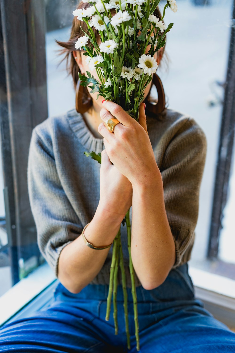 mulher cobrindo seu rosto com flores brancas