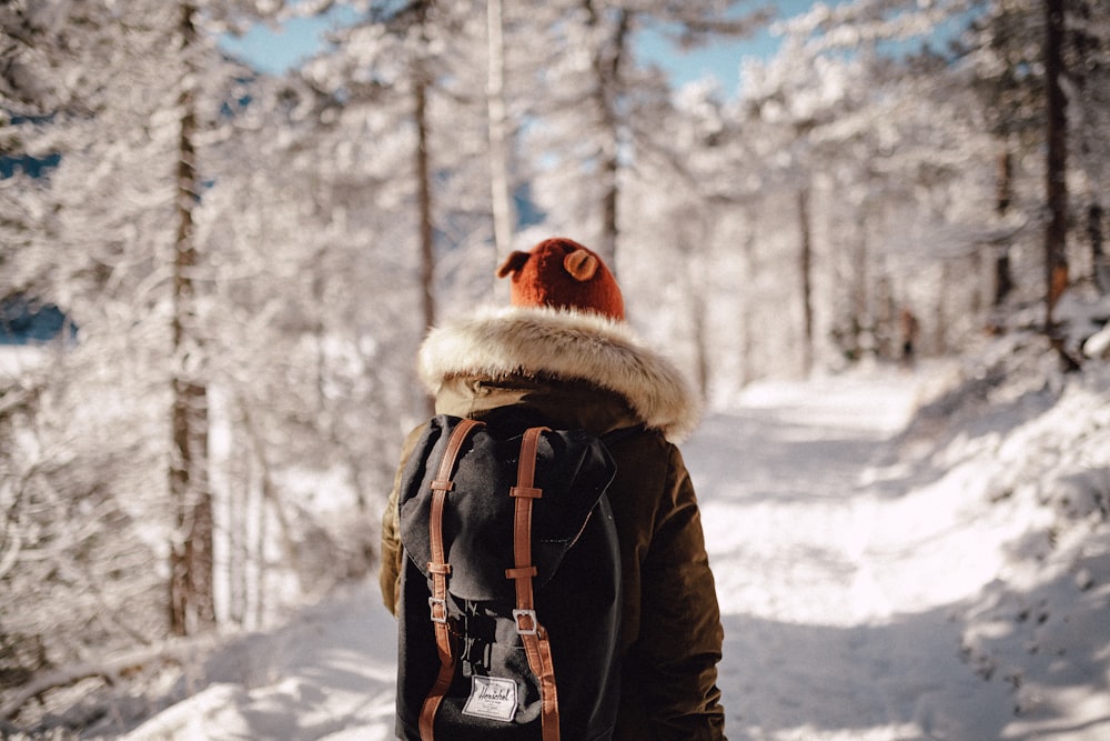 person walking on forest trail covered with snow