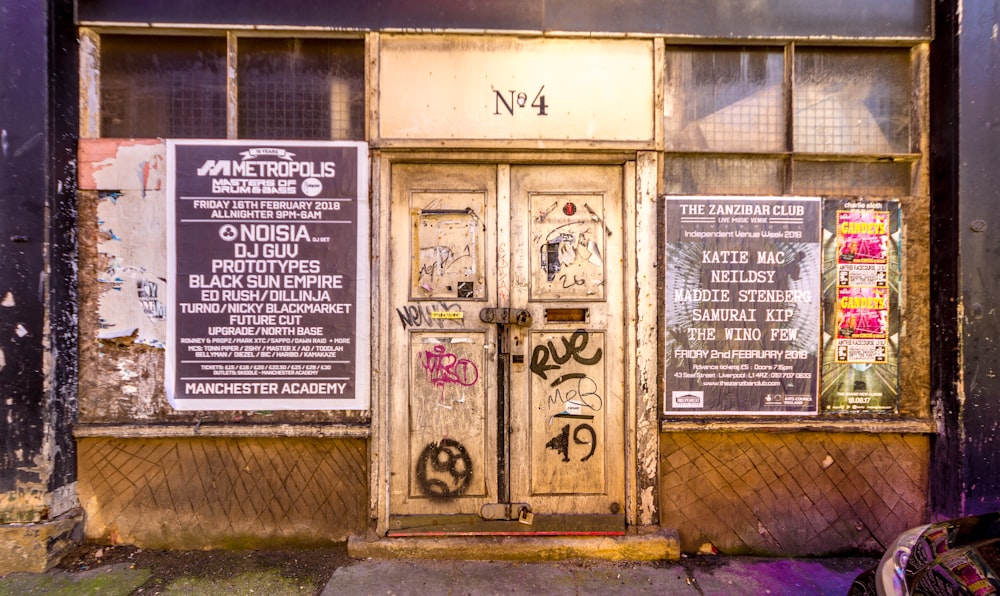 brown wooden door between posters