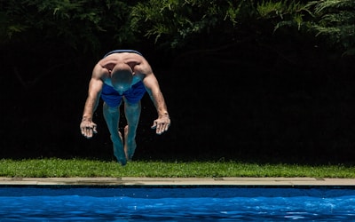 Young Congolese swimmer diving into a clear blue pool during a competition.