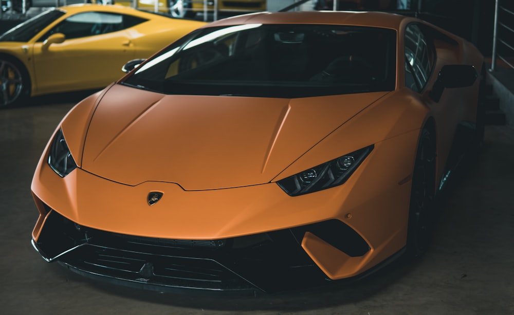 orange Lamborghini Huracan near yellow sports car