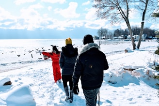 A group of smiling people wrapped in warm scarves enjoying a snowy walk near a frozen Finnish lake.