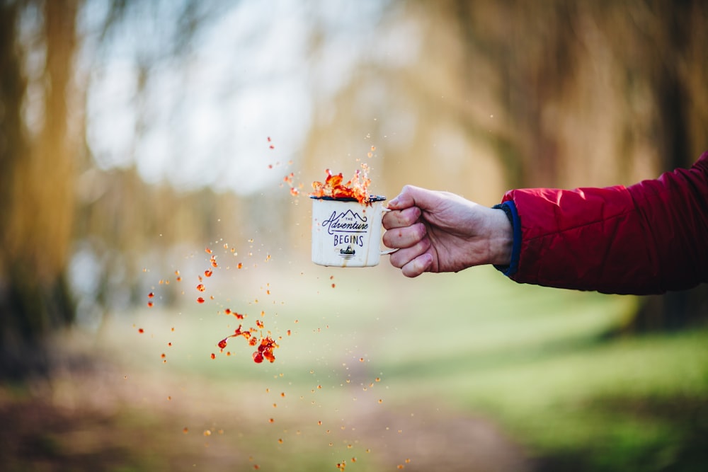 personne tenant une tasse en céramique blanche