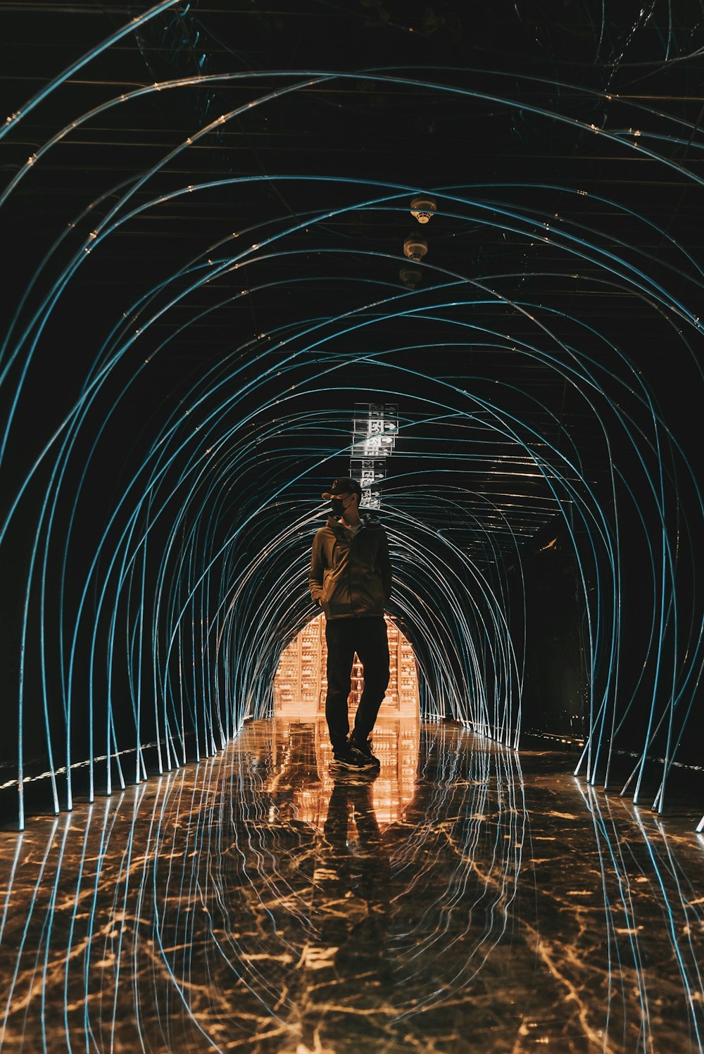 low-light photo of man man standing under tunnel