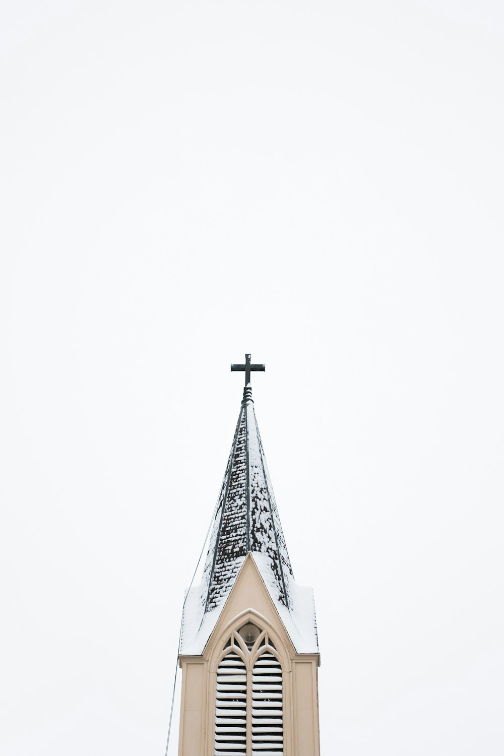 Torre da igreja bege e branca com cruz