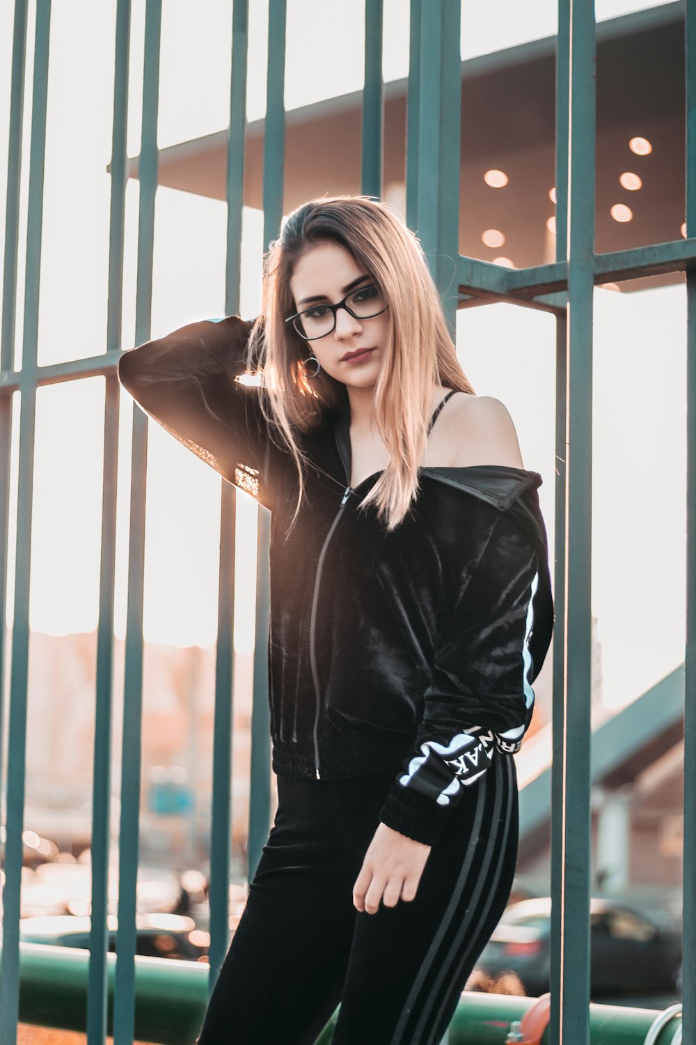 woman with eyeglasses leaning on green metal frame at daytime