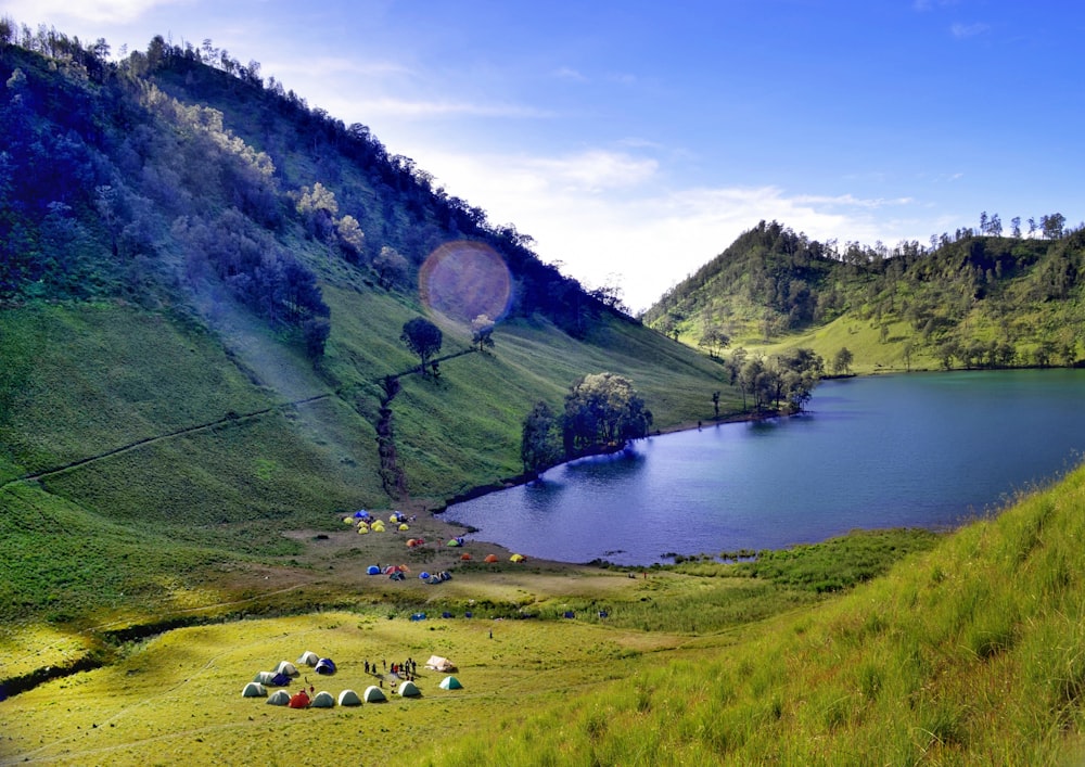 dome tents on mountain foot near body of water