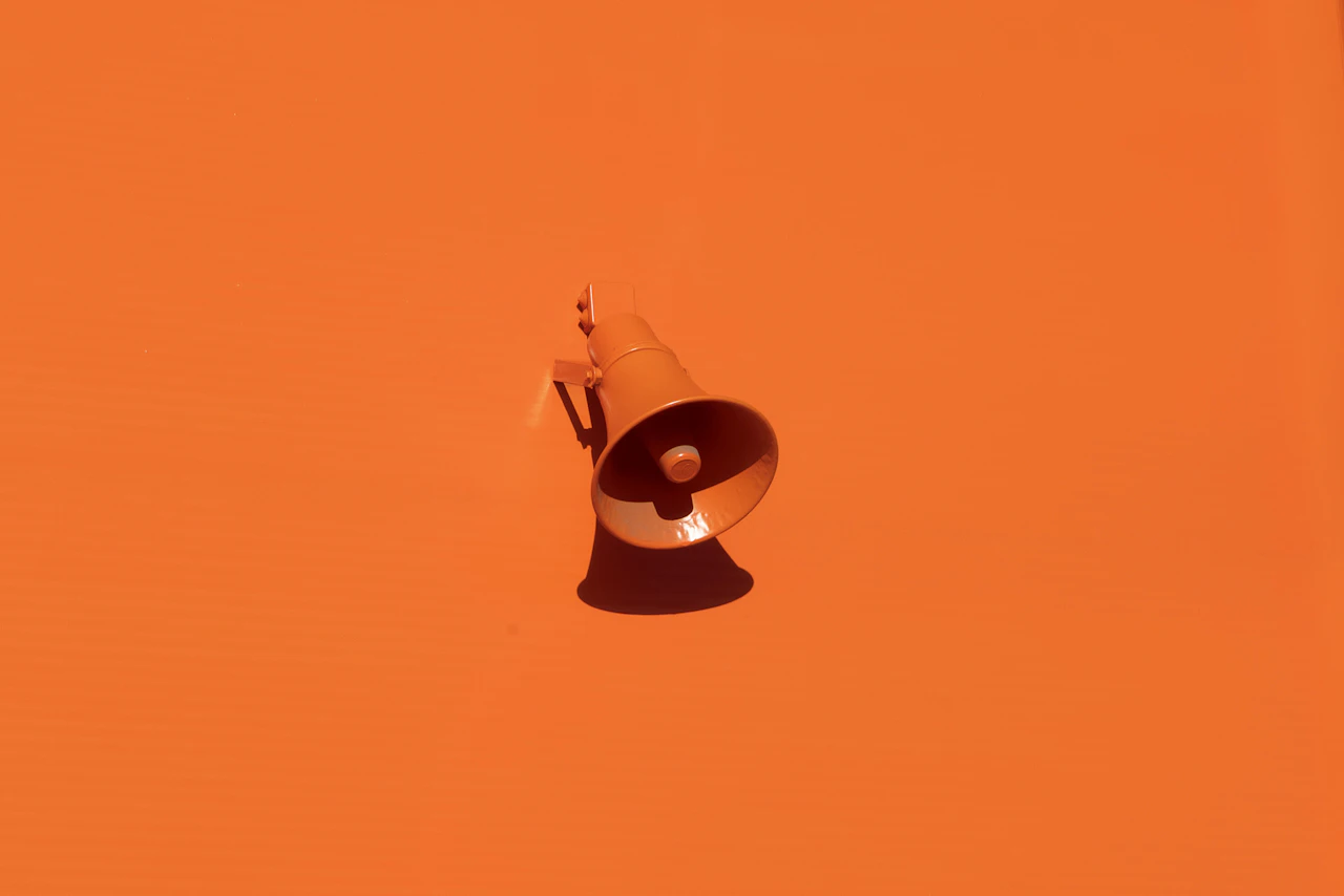 An orange megaphone mounted on an orange wall