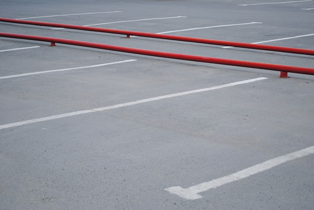 Barrera de riel de metal rojo en el área de estacionamiento de concreto