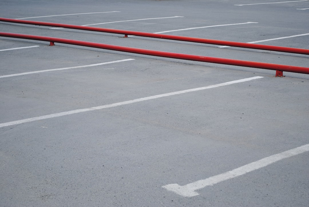 red metal rail barrier on concrete parking area