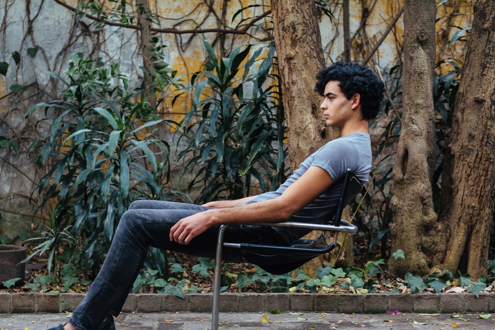 man sitting on gray steel chair