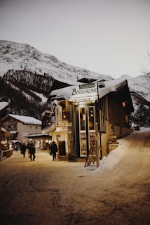 people walking beside buildings near mountain