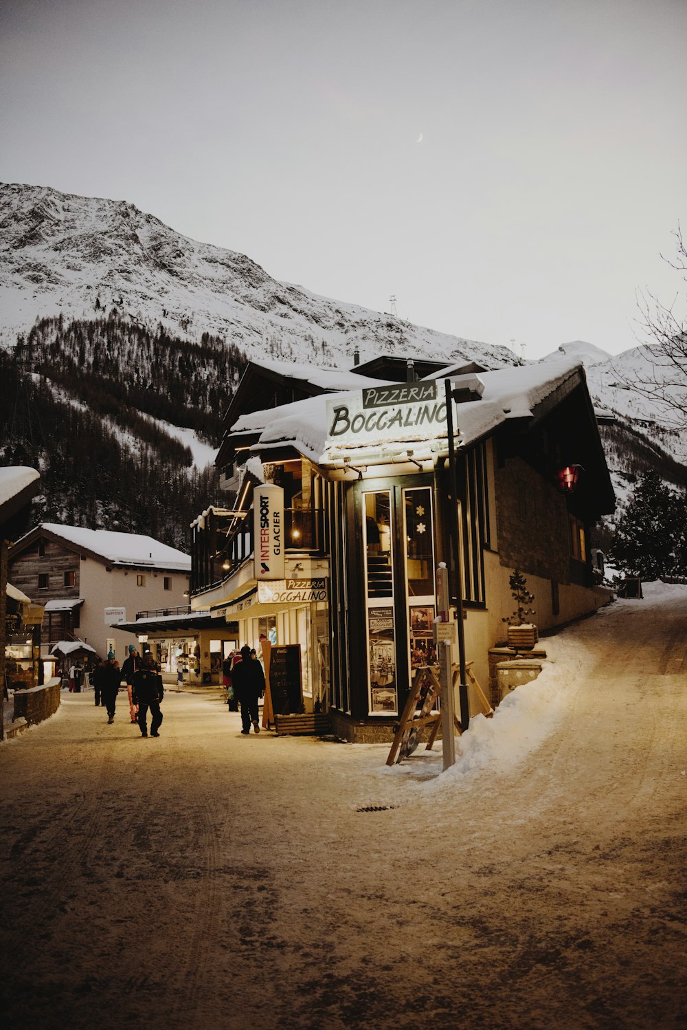 people walking beside buildings near mountain