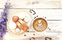 Artistic display of a morning coffee and grazing board combo, including fresh croissants, mixed berries, a latte, and honey drizzles on light mocha background