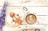 A latte with artful foam in a white cup sits on a rustic wooden surface, paired with an ornate plate featuring pastries, biscotti, a boiled egg, and some whipped cream dollops. Purple flowers and scattered coffee beans add to the aesthetic presentation.