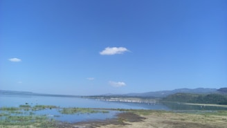 A serene Finger Lakes view with calm water and distant hills under a clear sky.