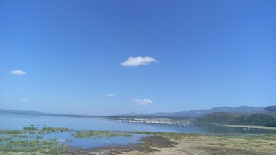 A serene Finger Lakes view with calm water and distant hills under a clear sky.