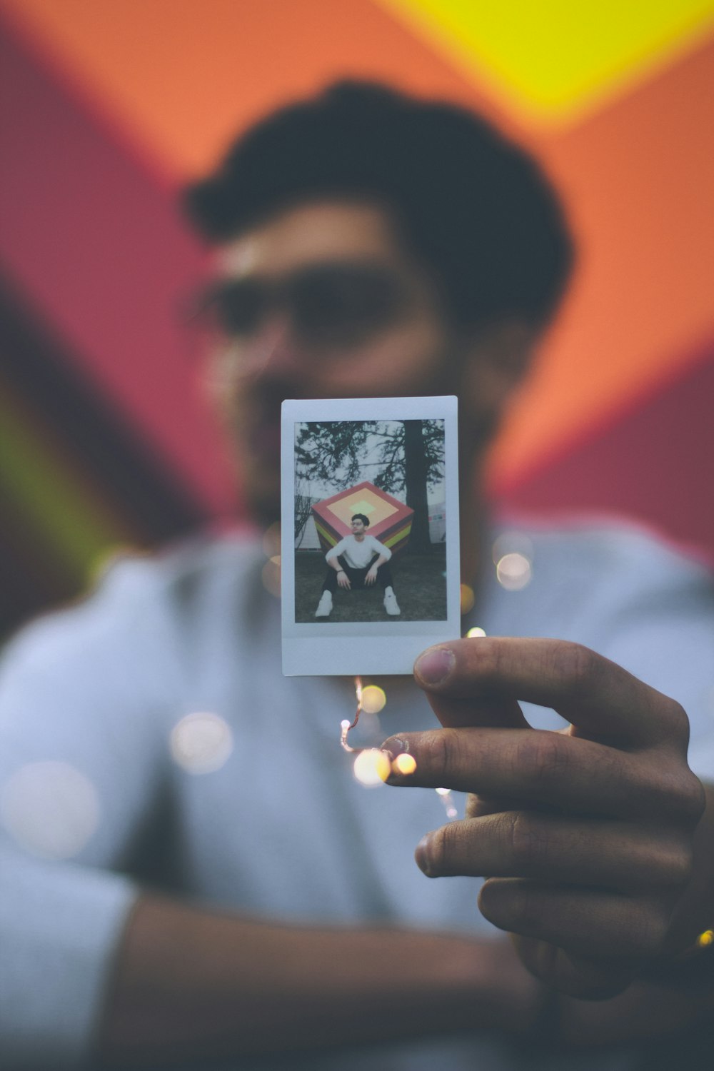 person holding photo of person sitting near tree