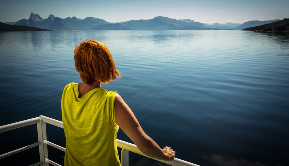 woman standing beside the fence looking at body of water