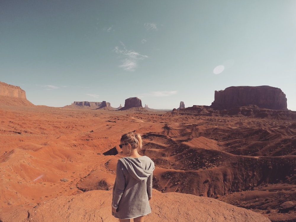 mujer con capucha gris mirando a Monument Valley durante el día