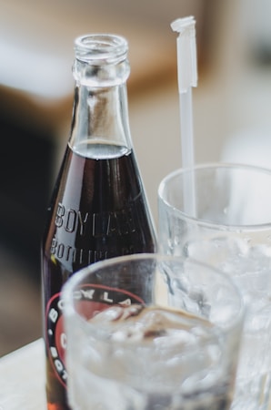 A glass bottle of Boylan soda is placed next to a glass filled with ice and a straw. The scene appears casual and relaxed, suggesting a refreshment setup.