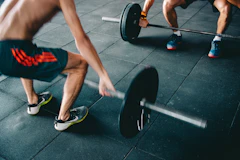 Homem realizando exercício de musculação para estimular o ganho de massa muscular na academia.