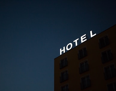 low-angle photo of Hotel lighted signage on top of brown building during nighttime