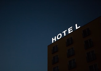 low-angle photo of Hotel lighted signage on top of brown building during nighttime