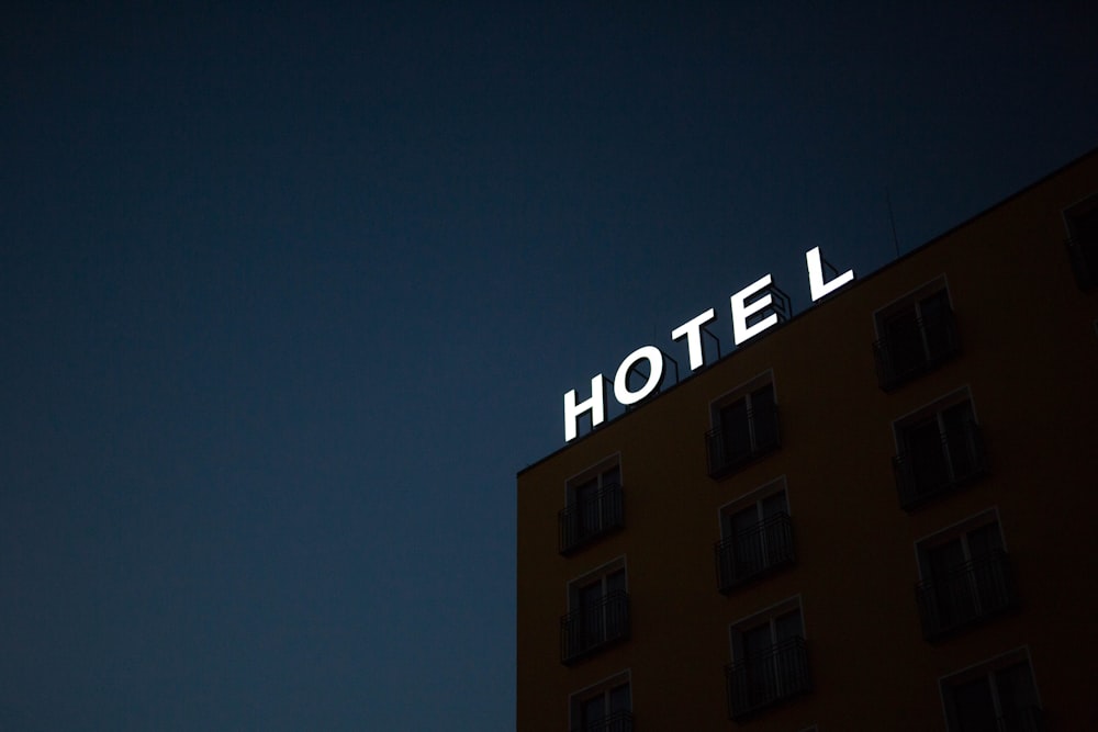 low-angle photo of Hotel lighted signage on top of brown building during nighttime