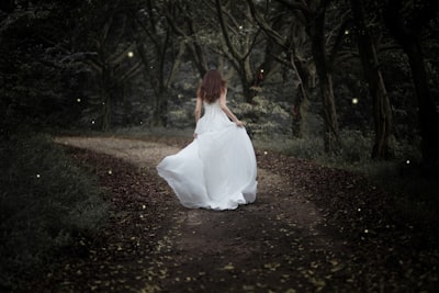 woman running on brown road covered with green leaf trees bride teams background