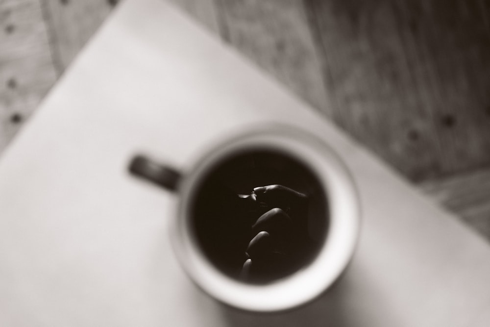 white and black ceramic mug on beige wooden table