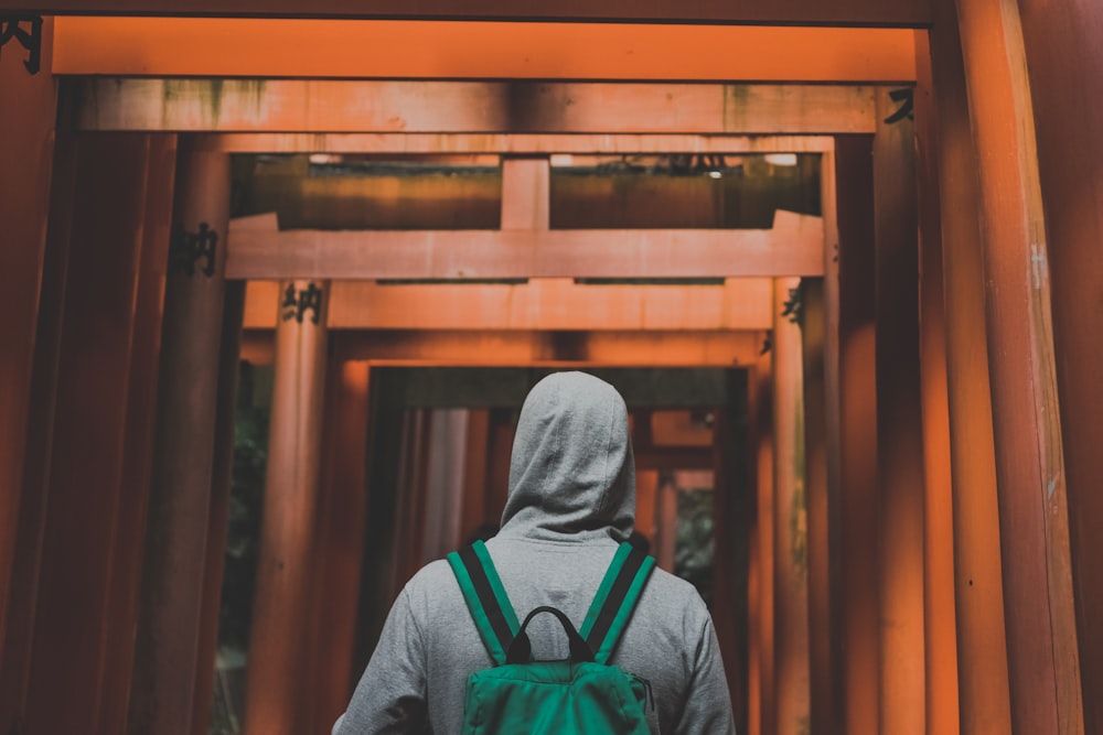 hombre con sudadera con capucha gris caminando sobre arcos de madera