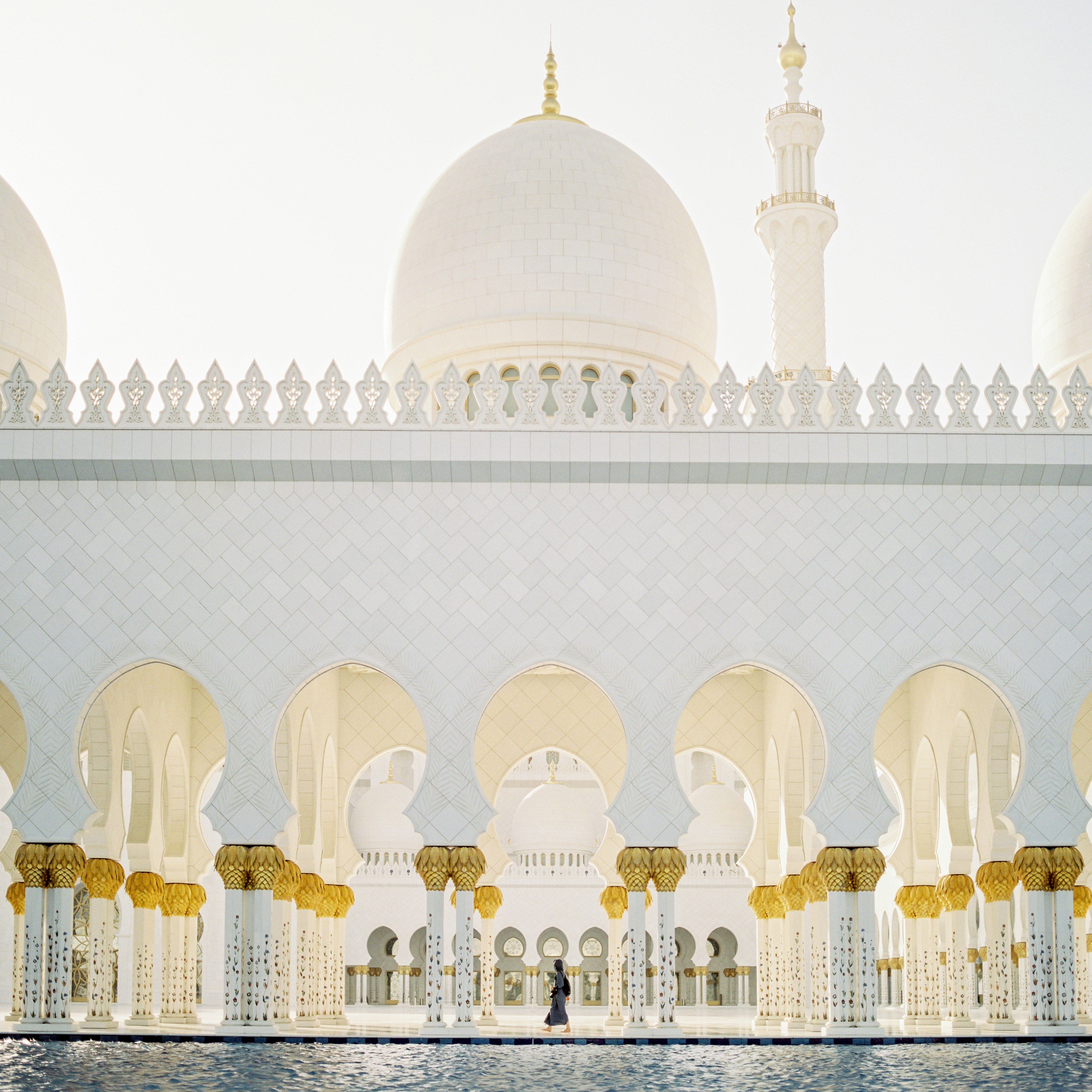 person walking inside white concrete mosque during daytime