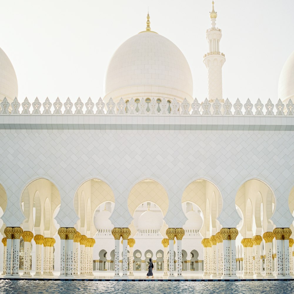 Persona caminando dentro de la mezquita de hormigón blanco durante el día