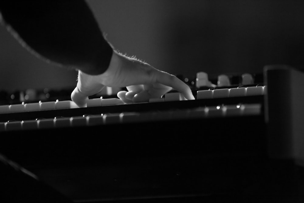 pessoa jogando teclado eletrônico na fotografia em tons de cinza