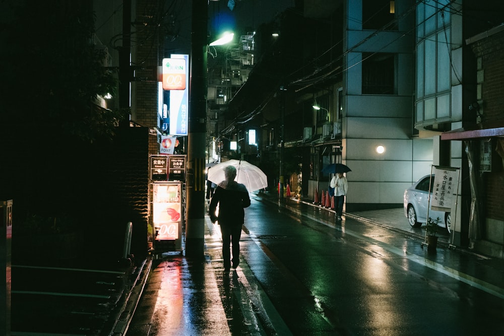 person holding umbrella near building at night time