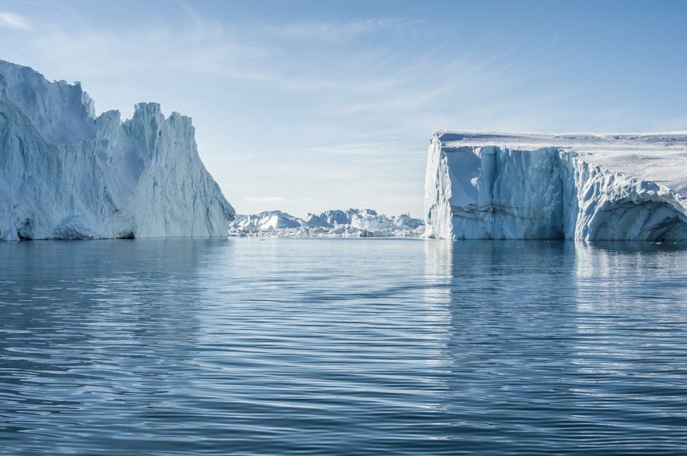 icebergs on body of water under blue and white sky at daytime