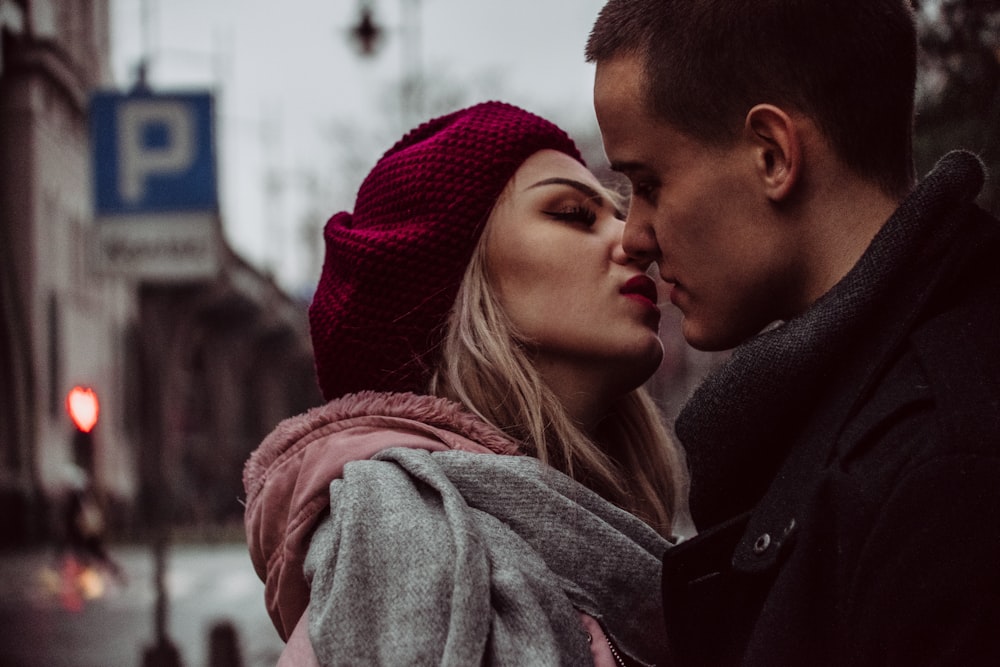 거리 표지판 옆에 키스하면서 서 있는 남자와 여자