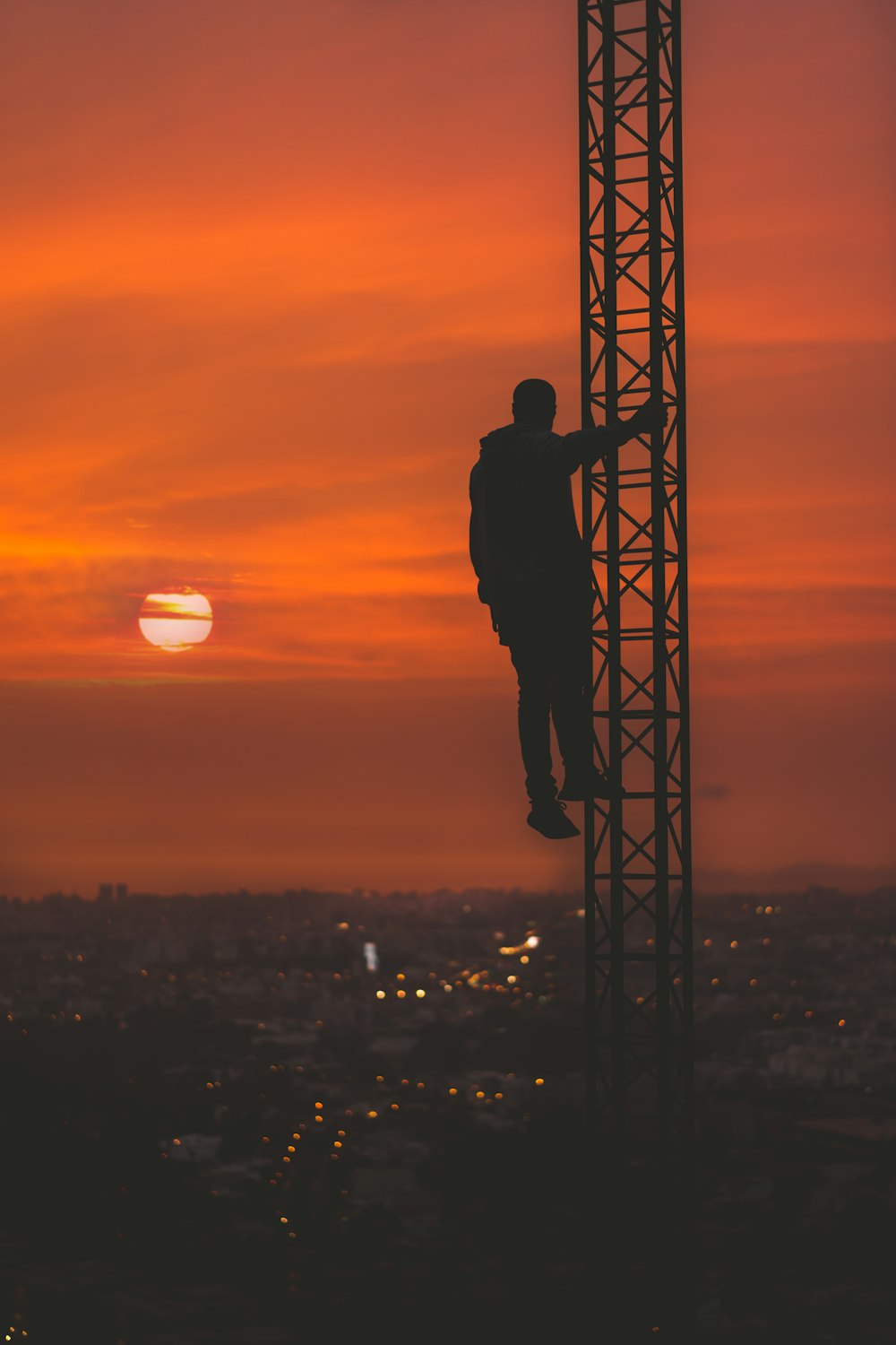 Silhueta do homem escalando a torre durante o pôr do sol