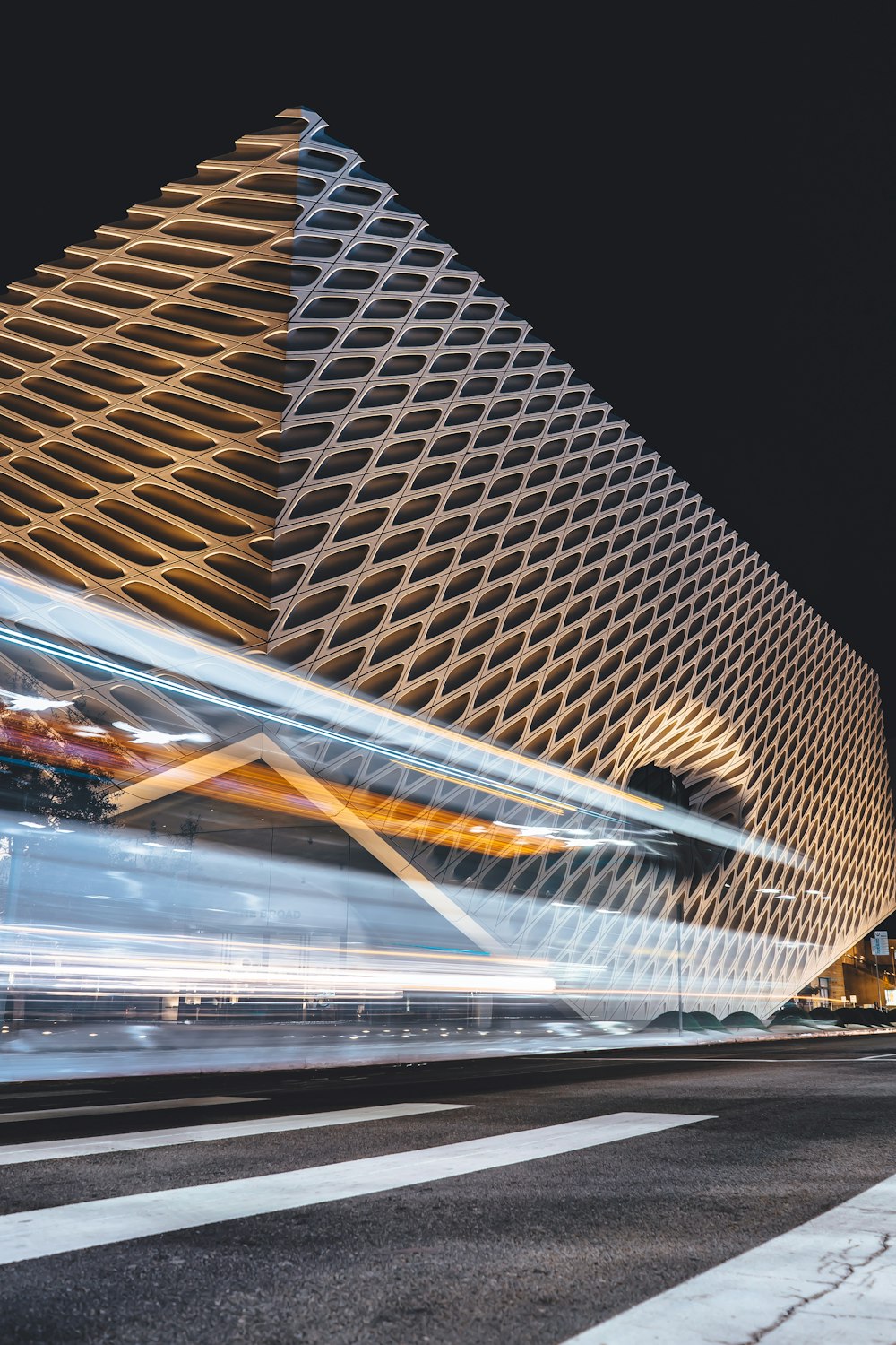 white and grey pedestrian lane paint front of glass building at night