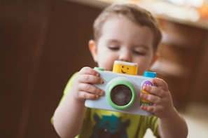 toddler holding white camera toy
