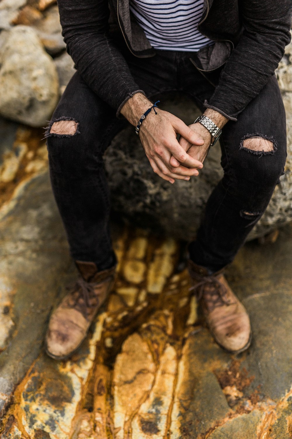 a man sitting on top of a rock next to a river